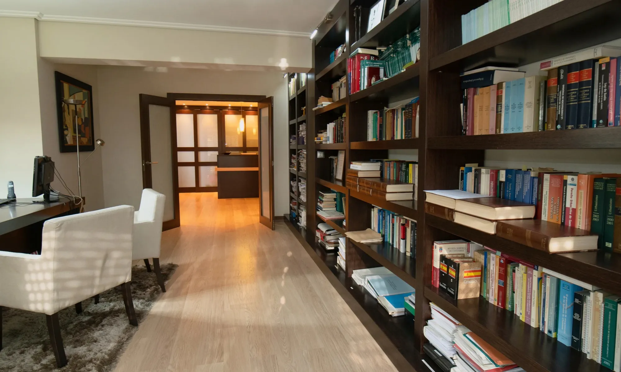 Biblioteca jurídica del despacho, con la mesa de trabajo a la izquierda y la recepción al fondo
