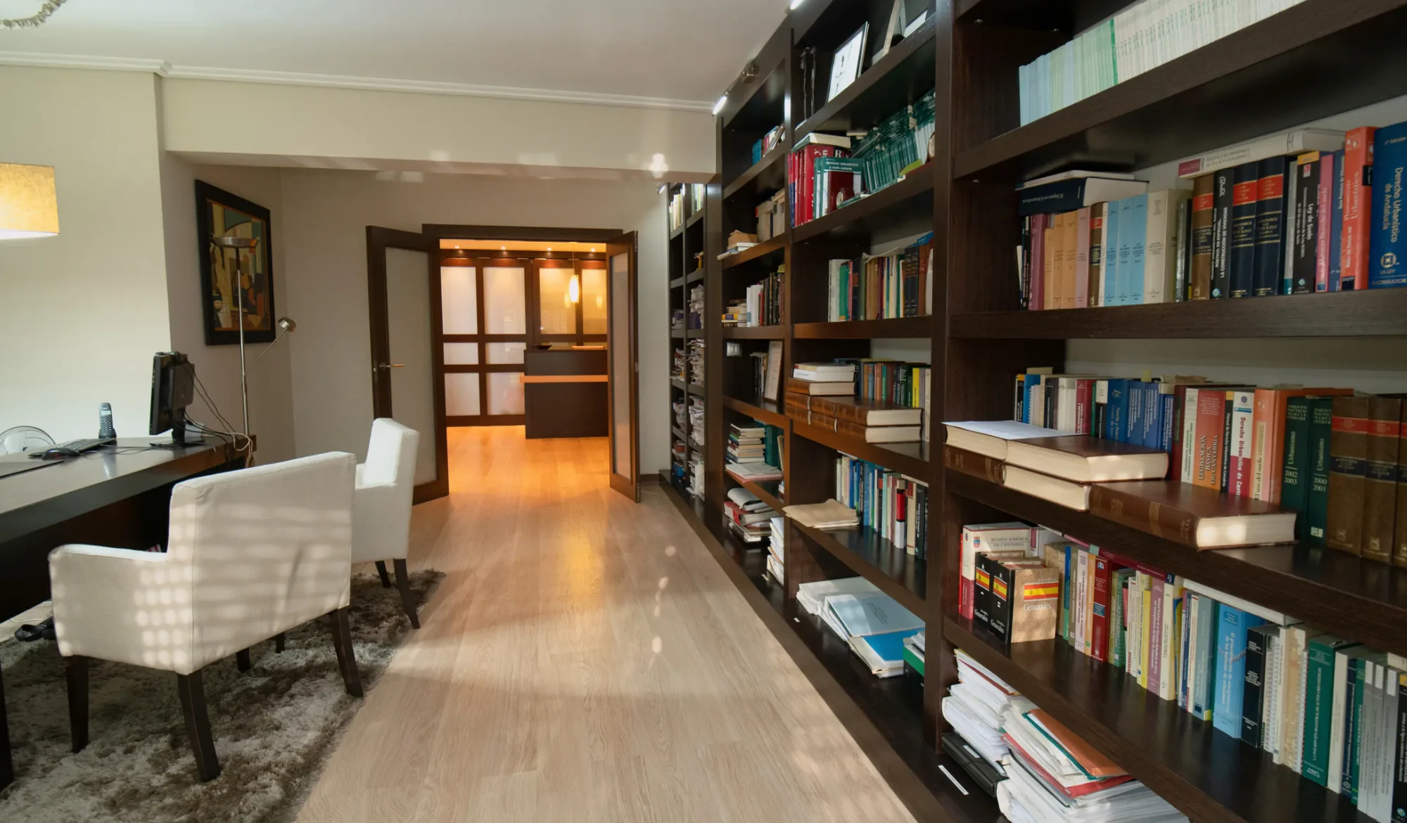Pasillo del despacho, con la biblioteca jurídica y la recepción al fondo